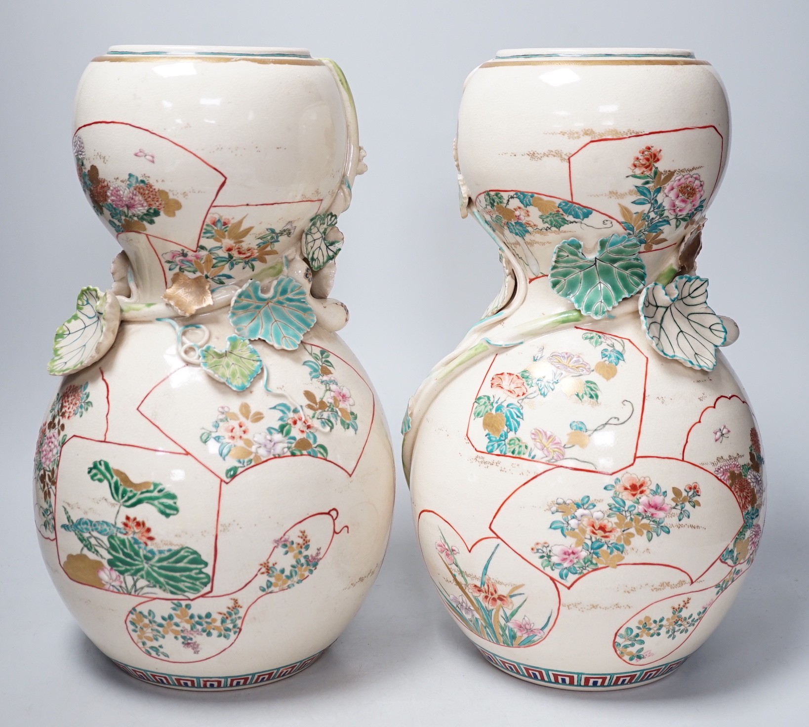 A pair of large late 19th century Satsuma pottery gourd shaped vases, each modelled with a gourd vine, 33cm tall